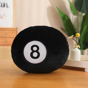 Plush black number 8 billiards ball pillow on a wooden table in a cozy home setting