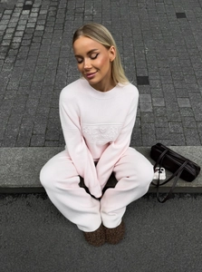 Detail of the pink knit sweater showing MEVMC Aesthetics embossed 3D lettering design