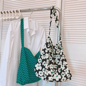 Detail view of green geometric and black floral canvas tote bags on a hanger