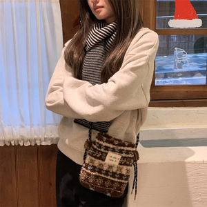 Detail of plush brown jacquard crossbody bag with brand label on textured fabric