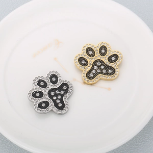 Pendentifs pattes de chat dorés et argentés avec cristaux brillants sur plateau blanc