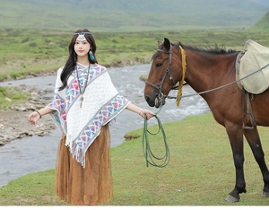 Close-up of white knitted poncho with colorful geometric patterns and decorative tassels