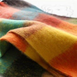 Detailed close-up of thick striped plaid scarf fabric with warm yellow and blue fringe