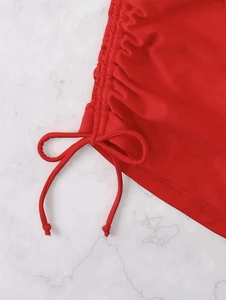 Detail of red bikini with side drawstring ties and elegant gathered fabric texture