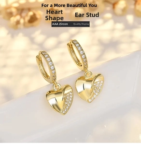 Detailed close-up of heart-shaped gold dangle earrings with sparkling AAA zirconia