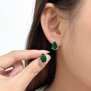 Detail of emerald green teardrop earring in 925 silver on model with natural lighting