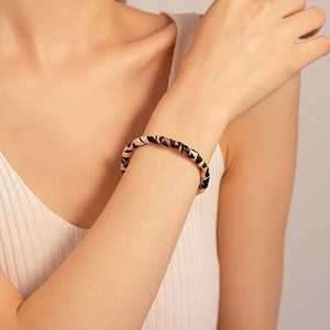 Detailed view of fashionable leopard print leather open cuff bracelet on wrist