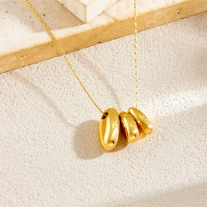 Collier minimaliste en acier doré avec trois pendentifs géométriques sur fond pierre