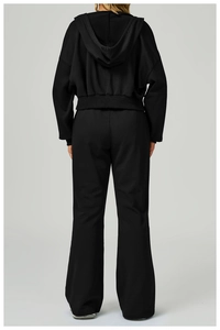 Rear view of model wearing a black two-piece tracksuit with hoodie and wide leg pants