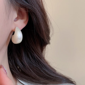 Detail view of elegant white teardrop earrings with a smooth pearlescent resin finish