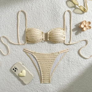 Detail of off-white bikini set with textured fabric and metal buckle on plush background