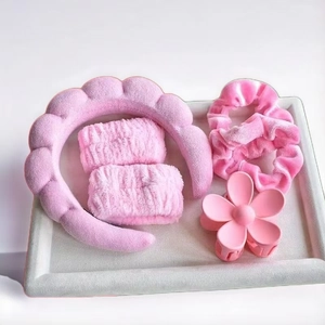 Pink personal care set with spa headband, wristbands, hair scrunchies, and flower clip