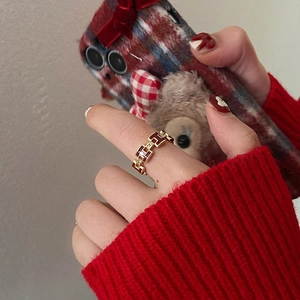 Close-up of a gold-plated H letter ring with red enamel and pavé-set zircons on hand