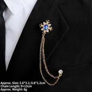 Detail of gold cross brooch with blue gemstones and chains on a black suit lapel