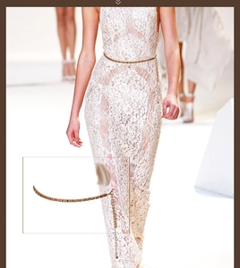 Detail of elegant gold metal waist chain with fringe tassel on white lace dress