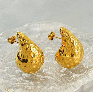 Macro detail of 18K gold teardrop earrings with hand-hammered texture and metallic finish