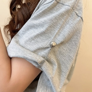 Close-up of silver metal chain and ball buckle on a rolled grey T-shirt sleeve cuff