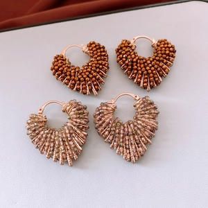 Détail de boucles d'oreilles cœur en perles de verre tissées main, bronze et or champagne