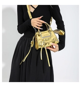 Detail of gold metallic patent leather city bag with rivets and heart mirror