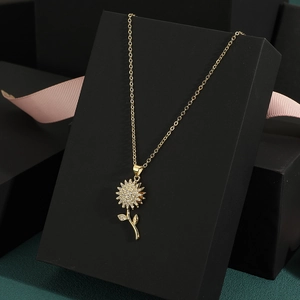 Golden rotating sunflower pendant necklace with zircon stones on a black gift box