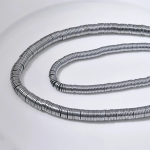Silberne Hämatit-Perlenkette auf einem weißen Teller mit metallischem Glanz im Fokus
