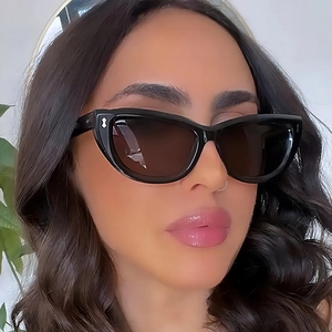 Occhiali da sole cat-eye da donna alla moda con montatura nera e lenti scure sul modello