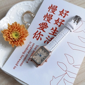 Detail of square rose gold quartz watch with white leather strap on a lifestyle background