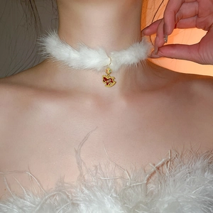 Detail of white plush choker necklace with gold metal trim and red rocking horse pendant