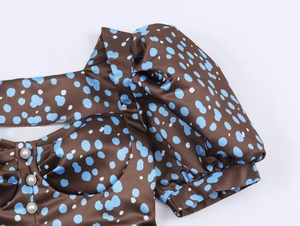 Detail of square neckline with three pearl buttons and puff sleeves on brown polka dot dress