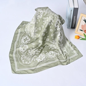 Detail of green silk square scarf with white paisley pattern and smooth rolled edges