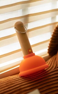 Detail of creative plunger night light with wooden handle and orange silicone lampshade
