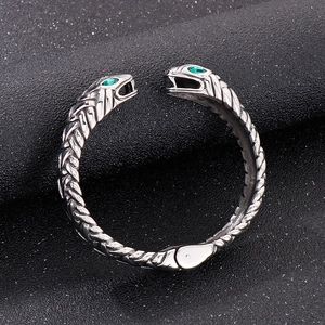 Macro detail of snake-shaped open bracelet with green gemstones and woven texture