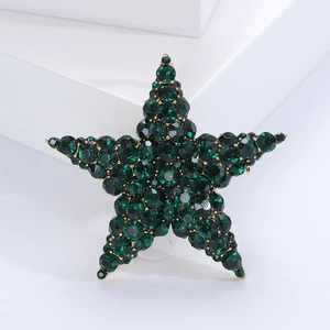 Macro detail of emerald green crystal star brooch with gold base on a white podium