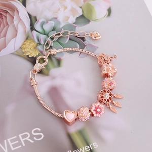 Rose gold DIY charm bracelet with floral beads and heart pendant on floral backdrop