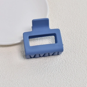 Close-up of matte blue square hair claw clip with hollow geometric design for hair styling
