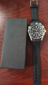 Macro shot of a men's diving watch with black wave dial and rubber strap on wood surface
