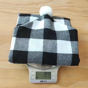 Détail d'une housse de chaise à carreaux noirs et blancs avec pompon pesant 97,9 g sur balance