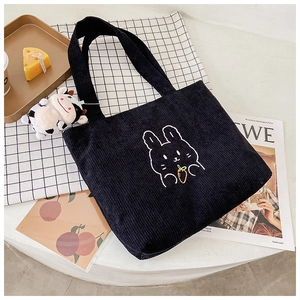 Close-up of black corduroy tote bag featuring an embroidered bunny holding a carrot