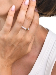 Detailed close-up of a minimalist pearl bead ring featuring a central gold metal bead accent