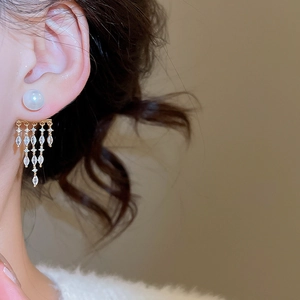 Detail of 14K gold plated tassel earrings with white pearls and sparkling zircons on model