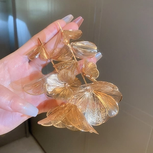 Macro detail of golden metal flower earrings featuring textured layered petals