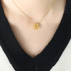 Golden titanium steel necklace with Chinese Xi character hollow pendant on a female model