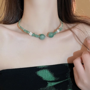 Dettaglio della collana di perline verdi con accenti di fiori di loto