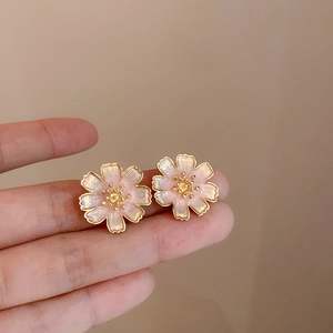 Dettaglio degli orecchini a fiore di ciliegio rosa con bordi dorati e texture lucida