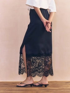 Detail shot of black satin midi skirt with elegant lace trim hem on model
