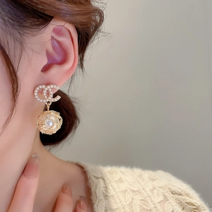 Elegant gold earrings with CC logo and faux pearl sphere drops worn by model