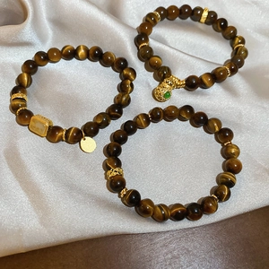 Macro detail of Tiger Eye beaded bracelets with golden gourd pendant on champagne silk
