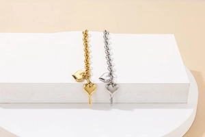 Close-up of gold and silver heart and key charm bracelets on a modern display stand