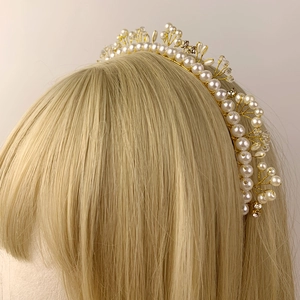 Elegant pearl and crystal bridal headband with gold wire weaving on model