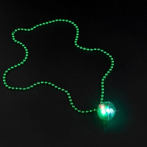 Macro detail of glowing green disco ball pendant necklace with green beaded chain